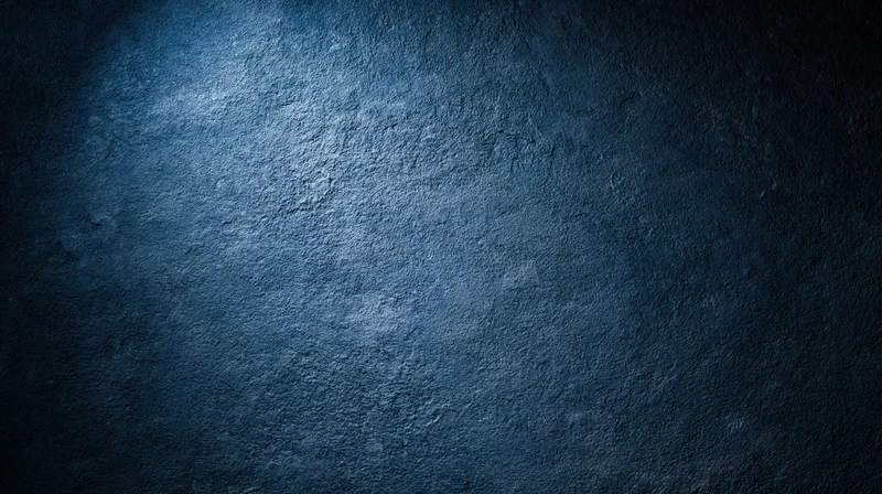 Textured blue concrete wall with spotlight and shadow, serving as a moody background