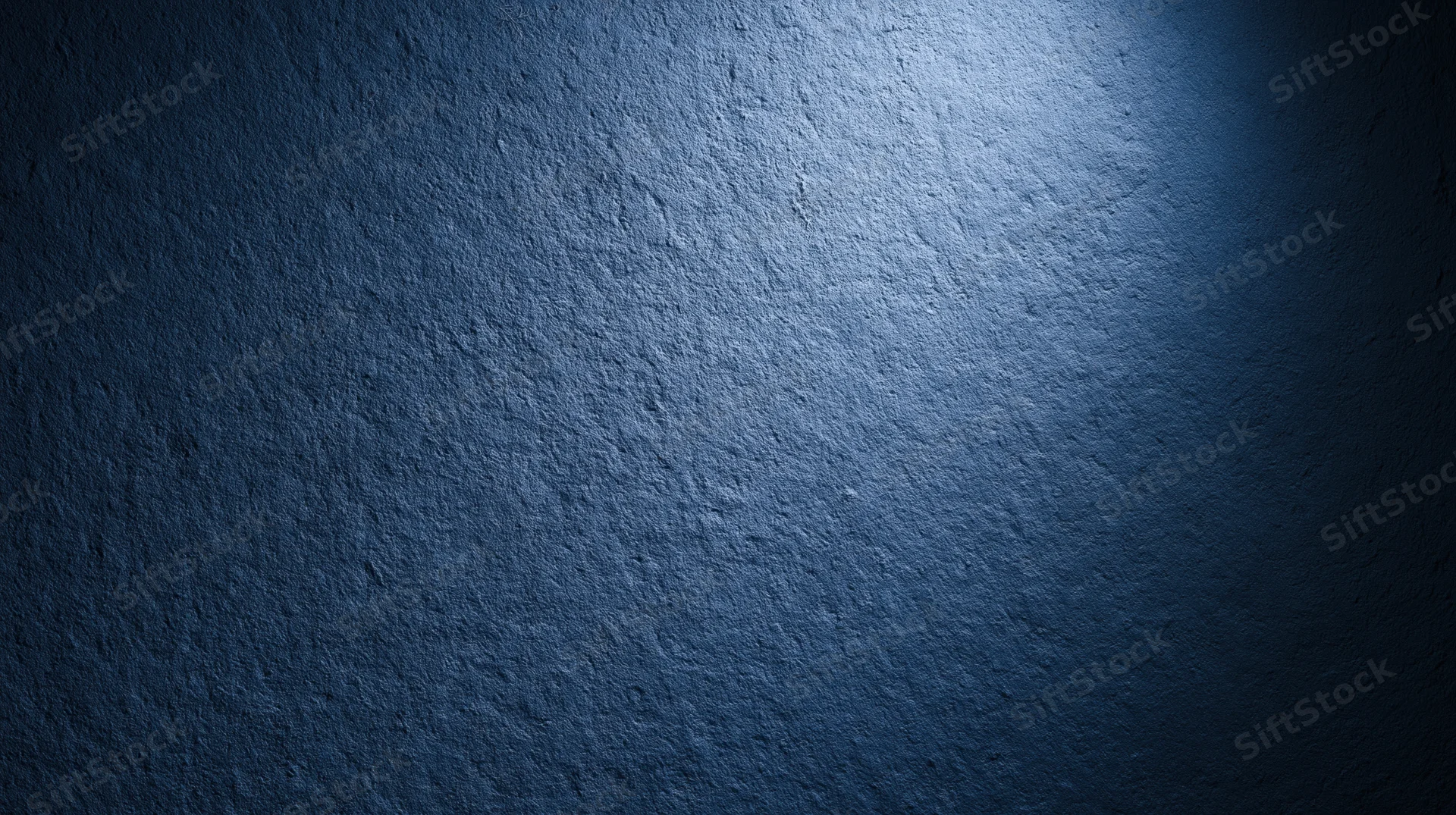 Textured blue wall illuminated by spotlight creating gradient shadow effect