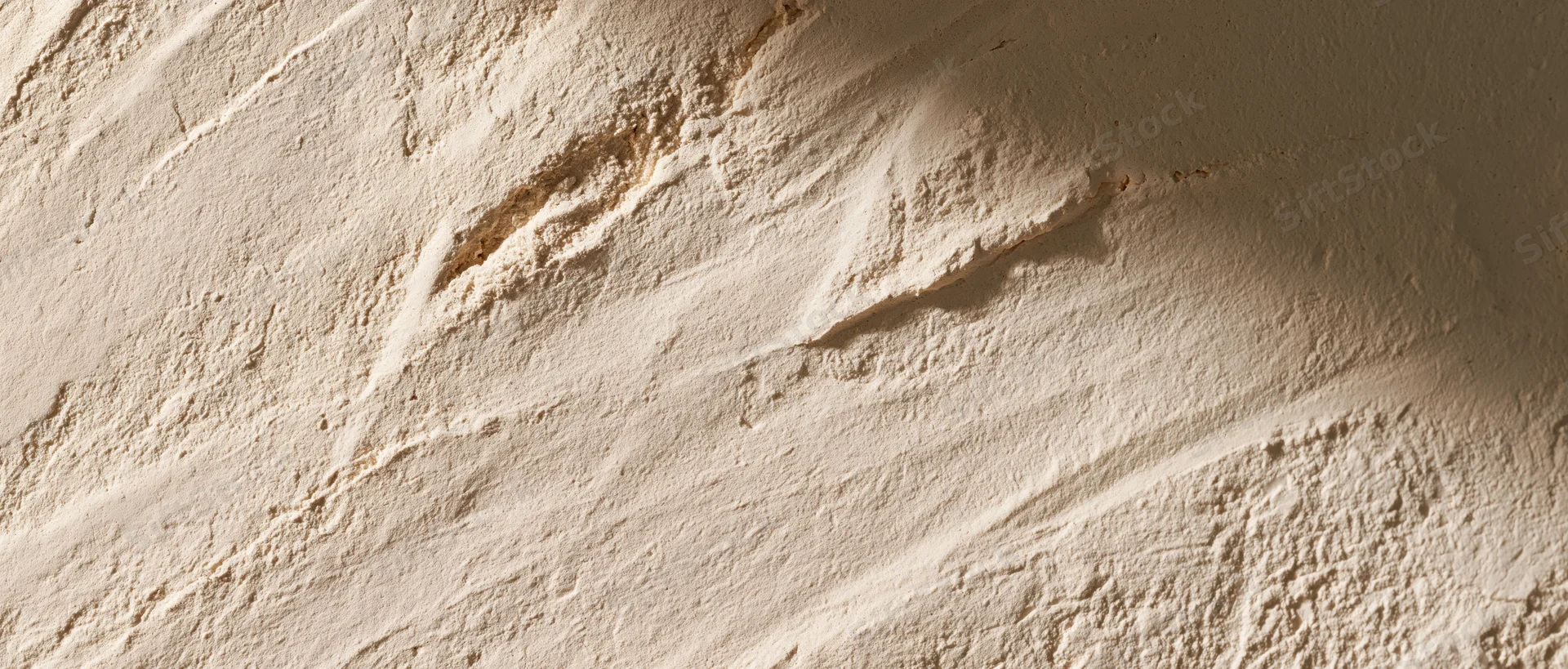 Close-up of textured plaster wall surface with visible brushstrokes and uneven finish
