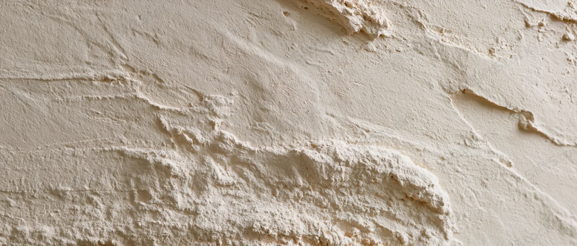 Close-up of textured plaster wall surface with uneven application and layered finish