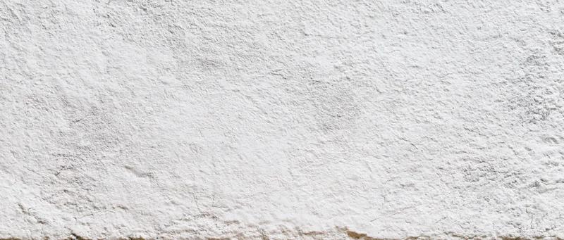 Close-up of a rough white plastered wall surface with uneven texture and subtle imperfections
