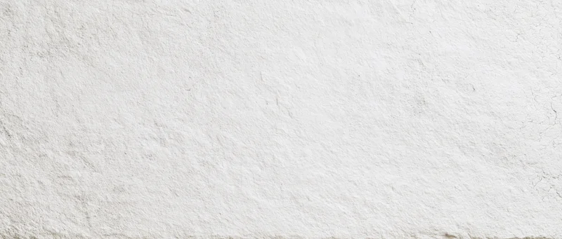 Textured white plaster wall surface with cracks and uneven finish
