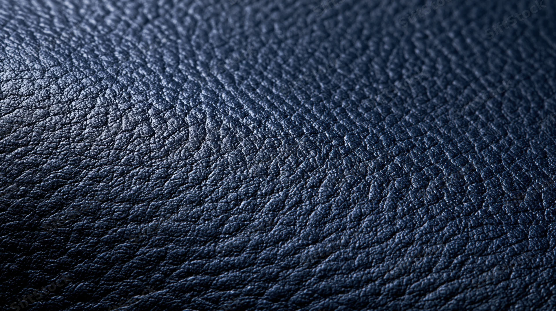 Closeup of dark blue leather texture showing fine grain pattern and subtle sheen