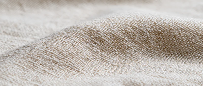Closeup of beige knitted fabric with visible texture and weave pattern