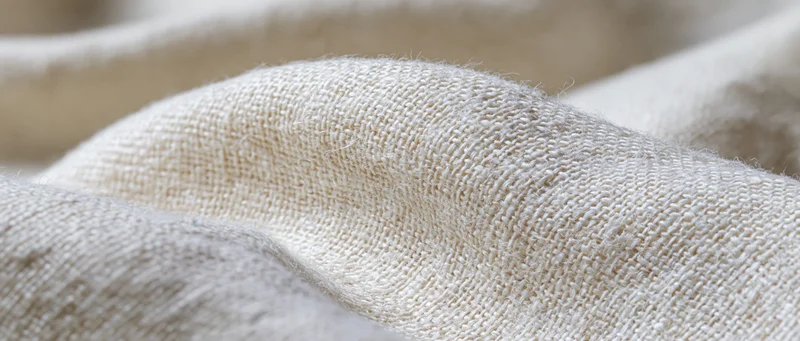 Closeup of natural beige woven fabric with soft texture and gentle folds