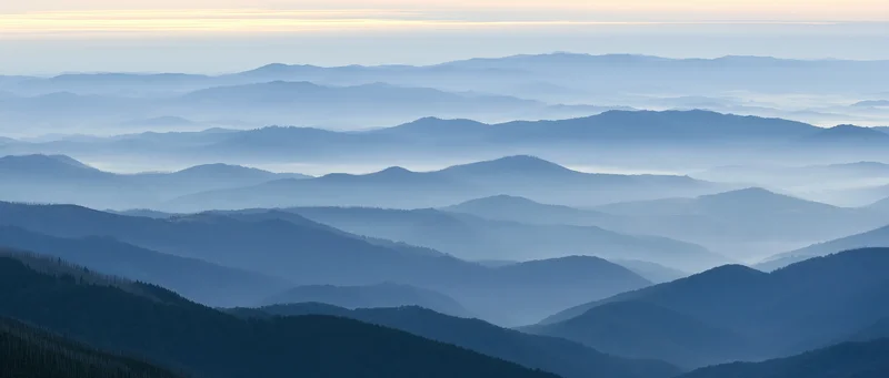 Layered mountain ridges receding into misty horizon under twilight sky