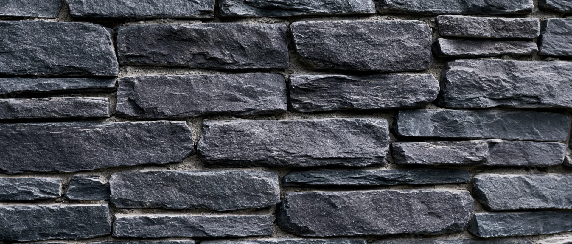 Dark gray slate stone wall with stacked horizontal pattern and mortar joints