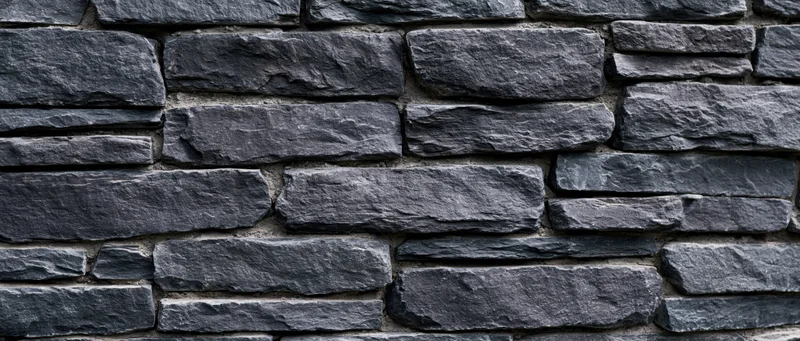 Dark gray slate stone wall with stacked horizontal pattern and mortar joints
