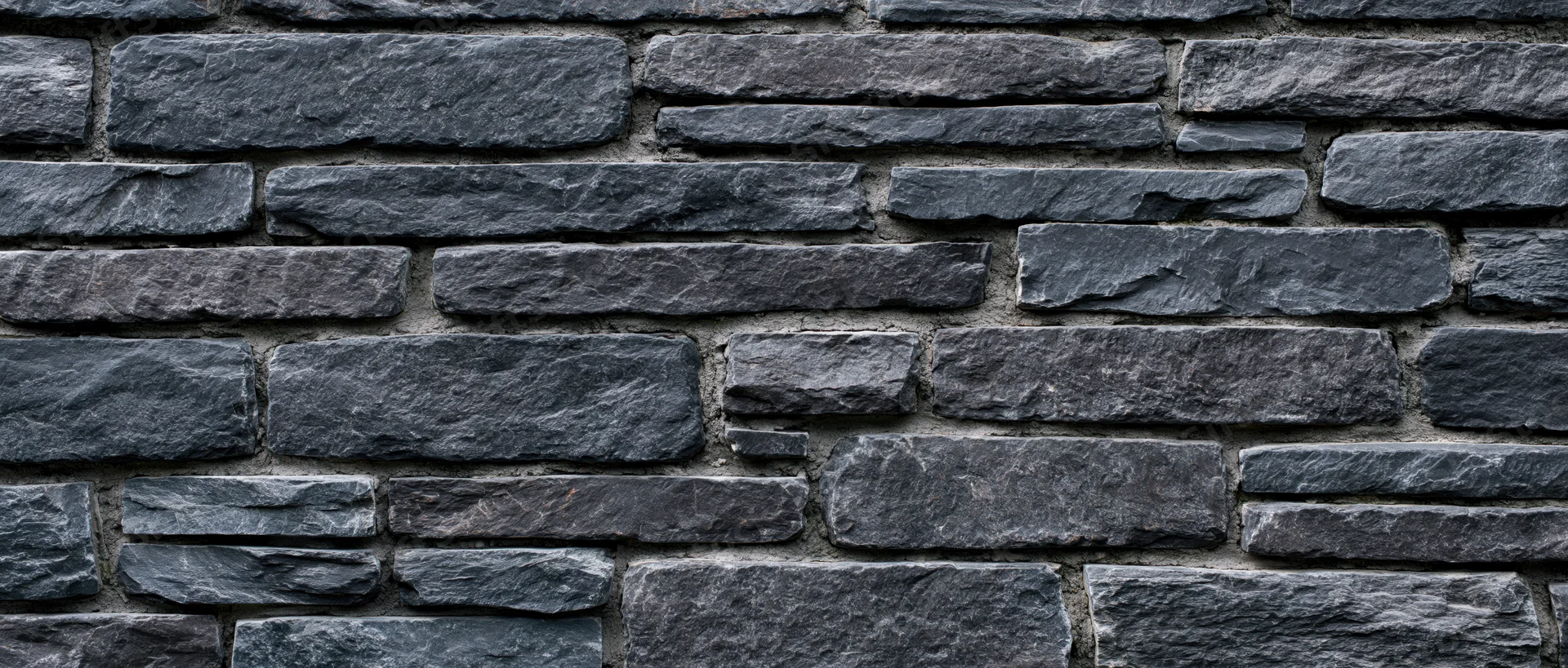 Dark gray stone wall with horizontal stacked masonry and mortar joints, exterior surface texture