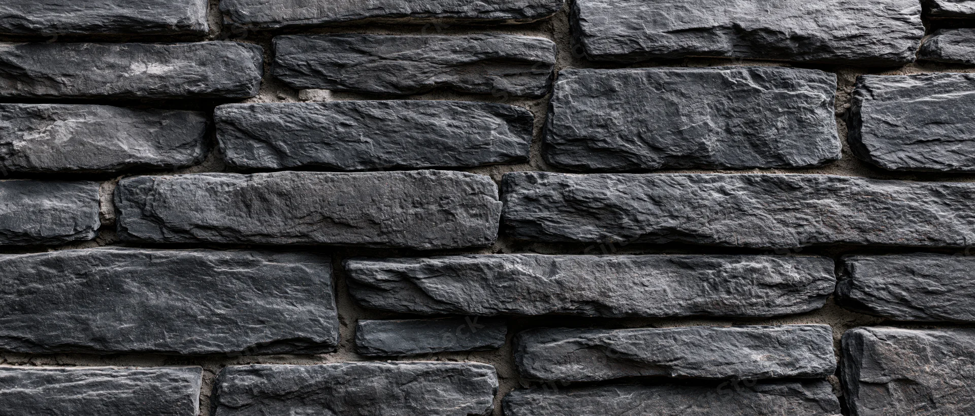Dark gray stone wall with horizontal stacked slate blocks and mortar joints, exterior architectural surface