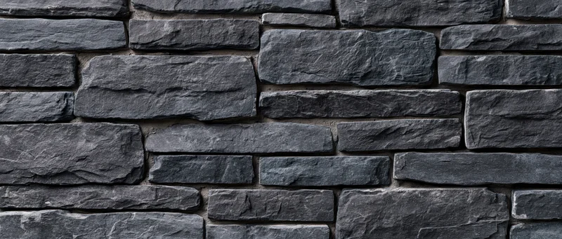 Gray slate stone wall with rough texture arranged in staggered pattern for exterior building facade