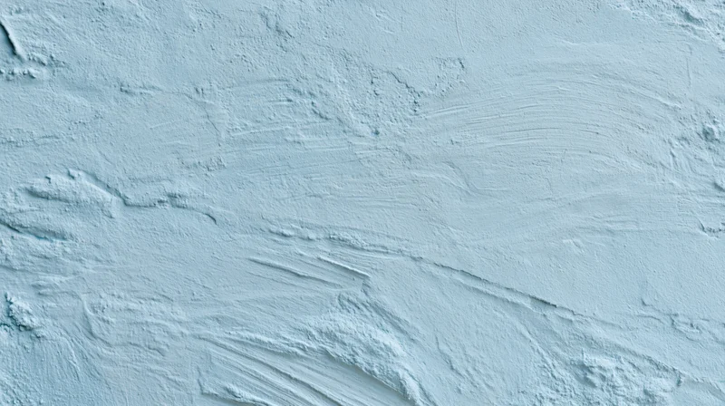 Light blue painted wall with visible brushstrokes and textured plaster finish