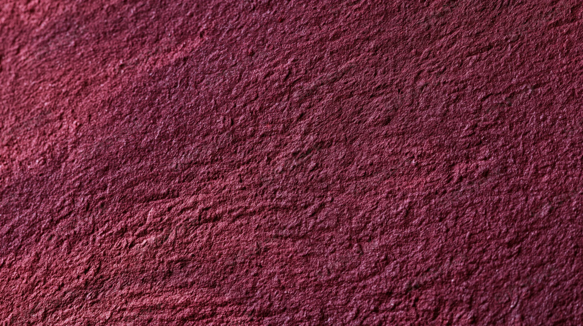 Closeup of a rough maroon textured surface with granular details and uneven finish