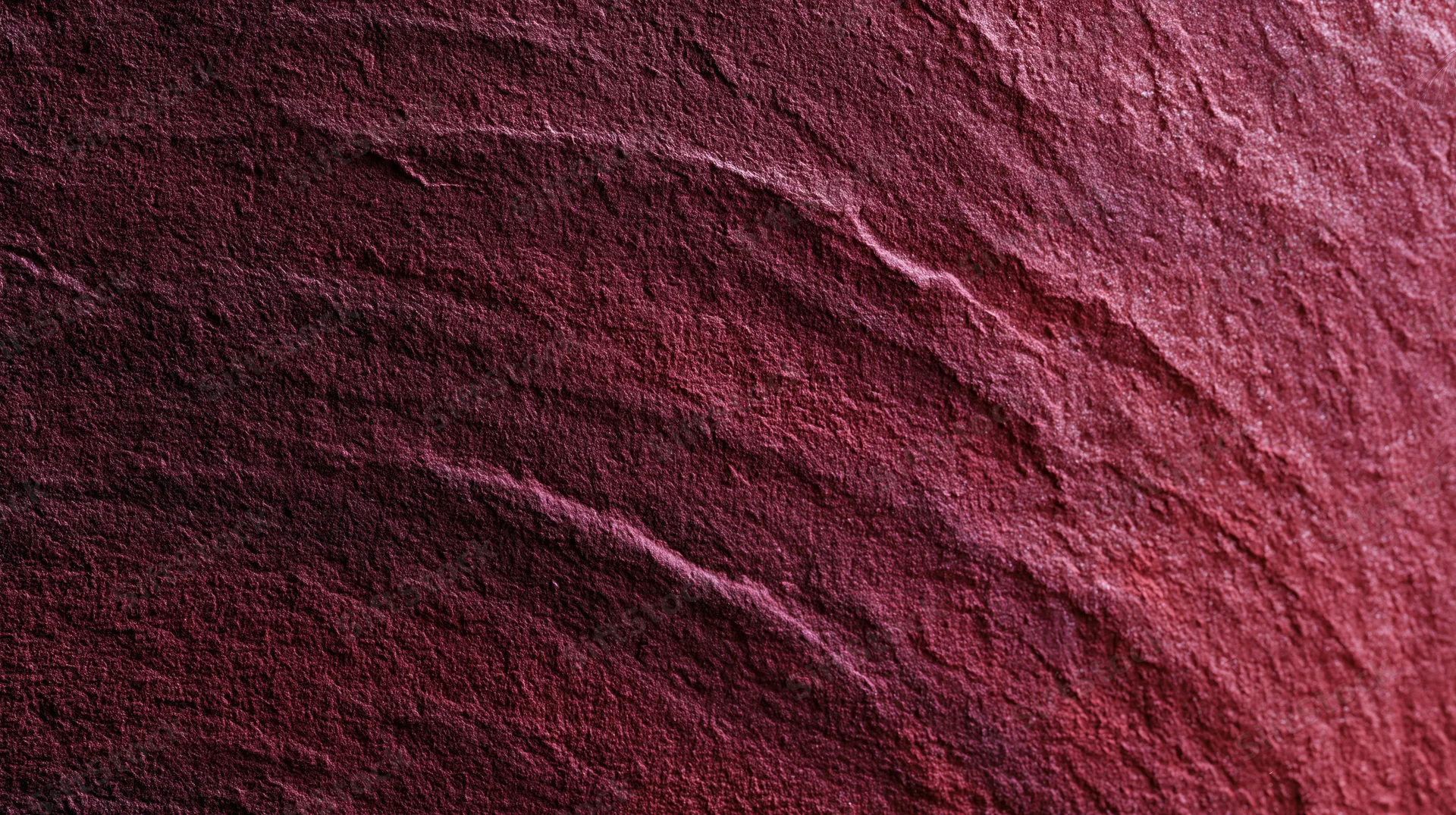 Closeup of red stone surface with natural striations and rough texture