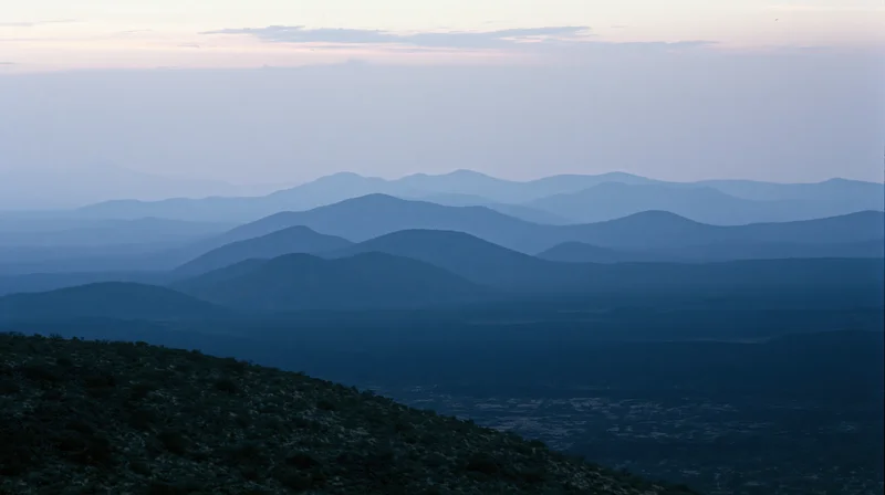 Layered mountain ridges receding into the distance under a hazy twilight sky