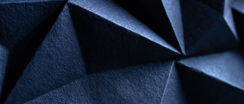 Dark blue faceted geometric surface with sharp angles and shadows