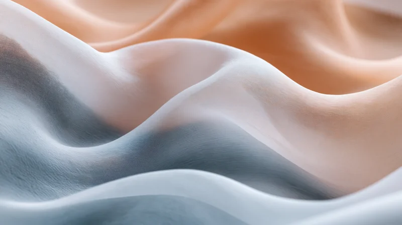 Flowing silk fabric draped in soft waves with light and shadow creating a smooth, undulating surface