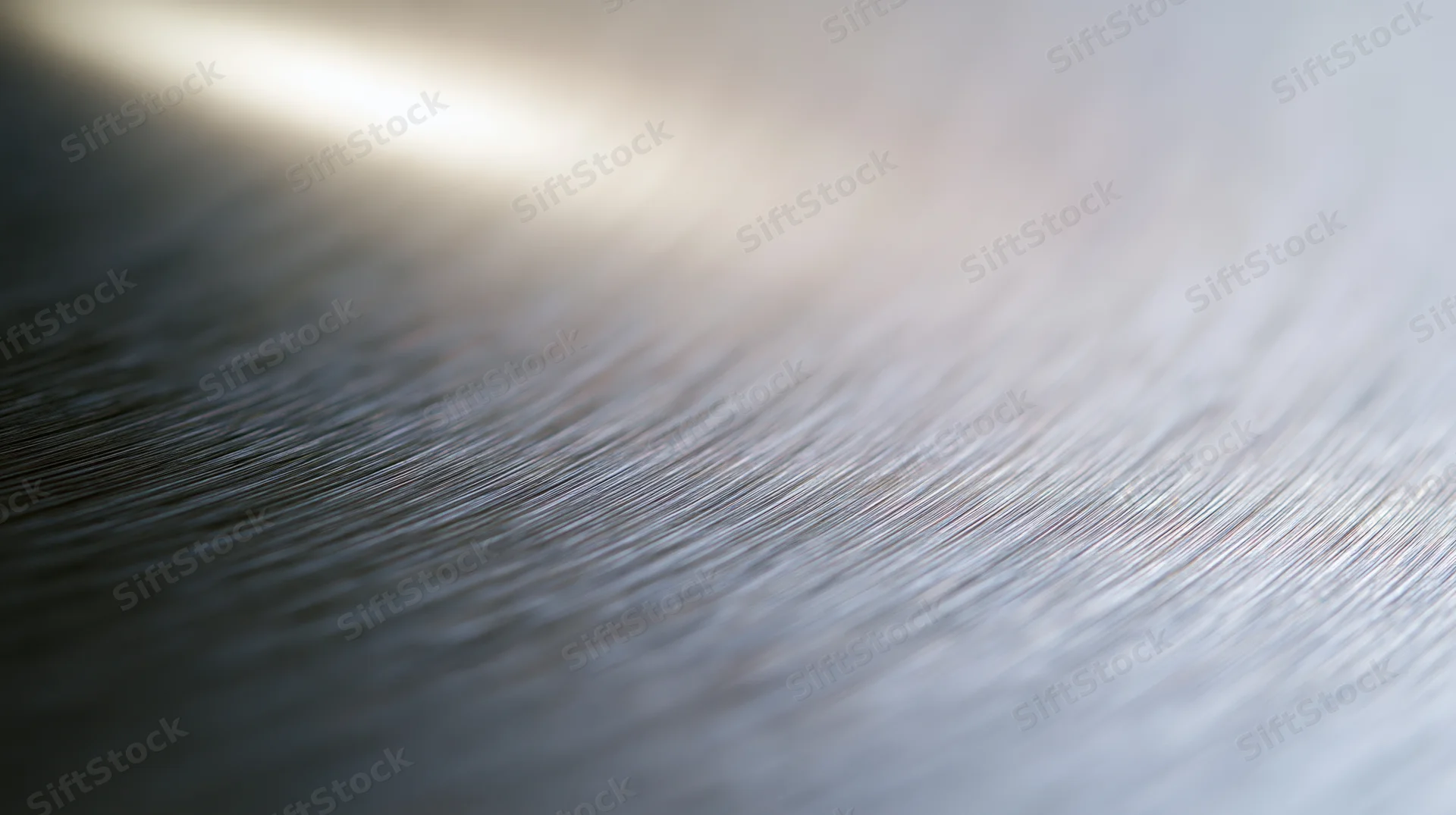 Closeup of brushed stainless steel surface showing fine linear texture and reflective sheen