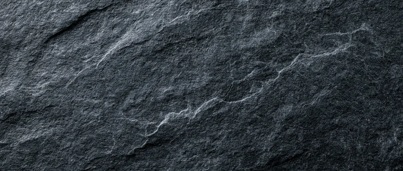 Closeup of dark slate stone surface with natural cracks and texture