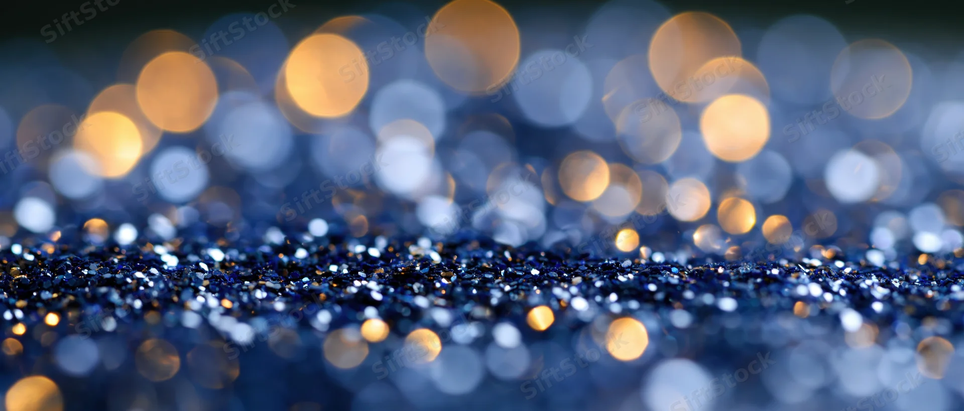 Blue glitter surface with golden bokeh lights in background
