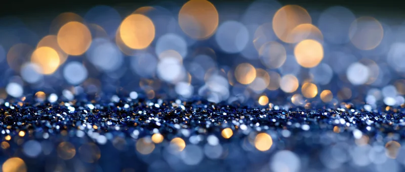 Blue glitter surface with golden bokeh lights in background