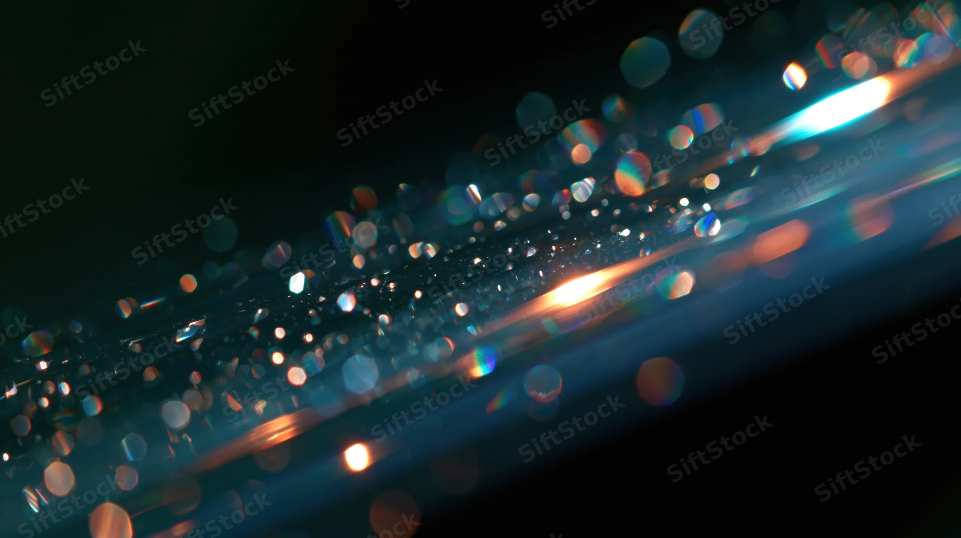 Abstract bokeh lights with rainbow refractions on dark background