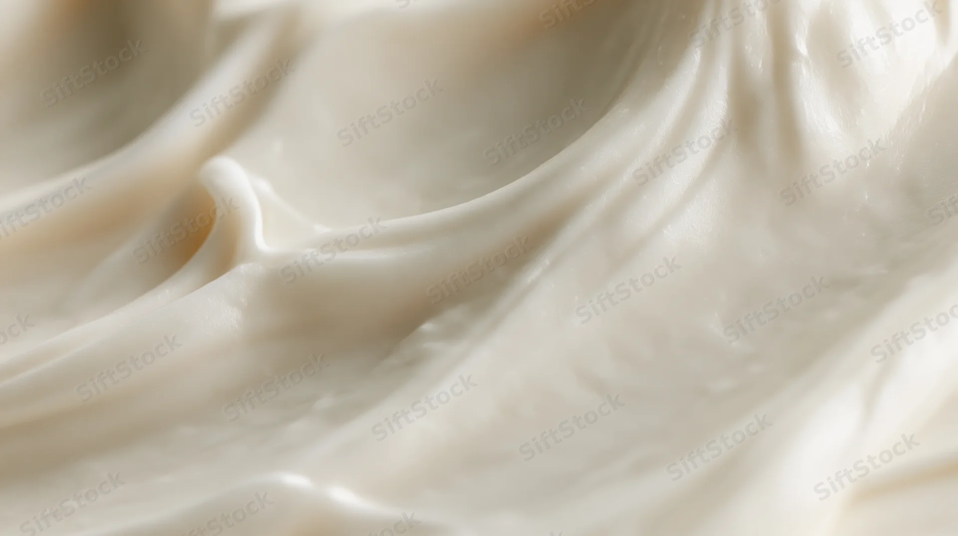 Closeup of white cream frosting in smooth swirls with glossy texture