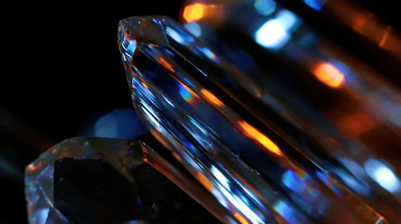 Closeup of a faceted diamond reflecting blue and orange light against a dark background