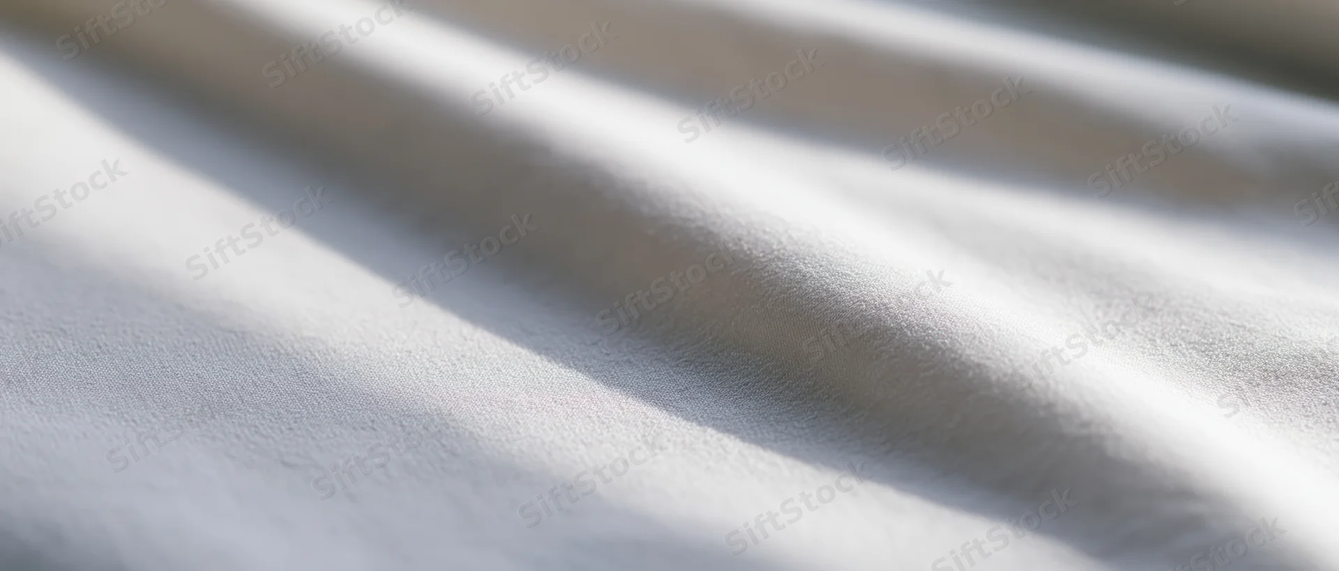 Draped white fabric with soft folds and natural light creating shadows and highlights
