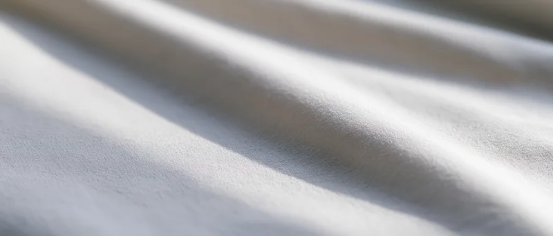 Draped white fabric with soft folds and natural light creating shadows and highlights