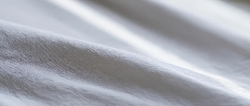 White fabric with soft folds and natural light creating gentle shadows across its surface