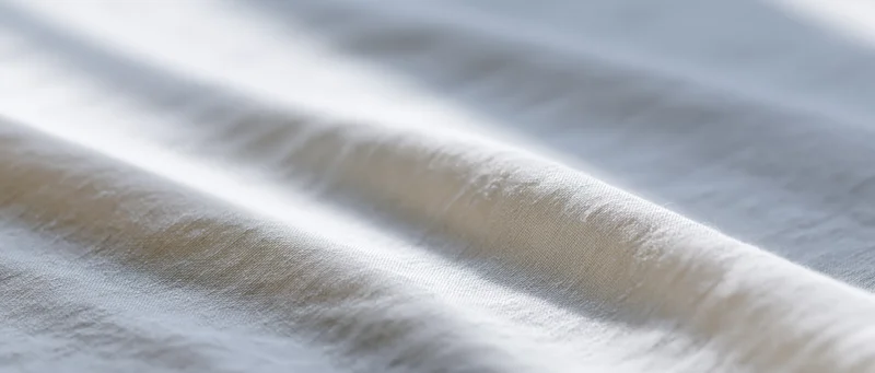 Closeup of white fabric with soft folds and natural light highlighting texture
