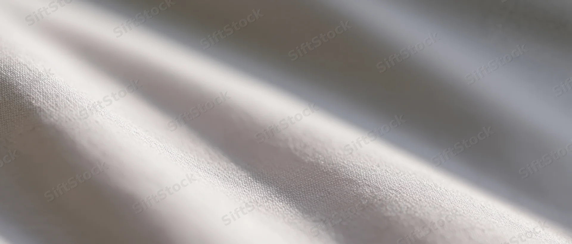 Closeup of white fabric with soft folds and natural light creating subtle shadows and texture