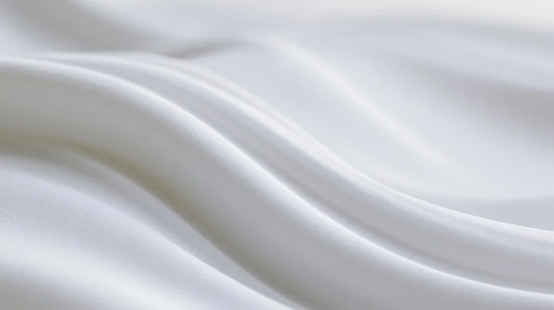 Flowing white silk fabric draped in soft waves with smooth texture and subtle sheen