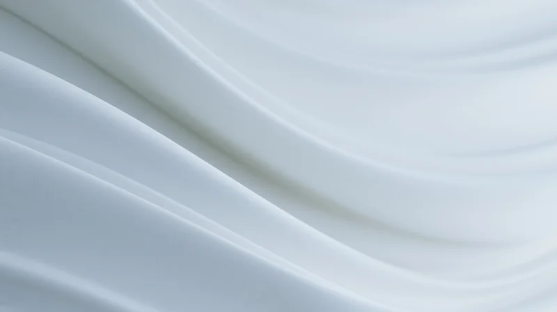 Flowing white fabric draped in soft curves creating a smooth abstract background