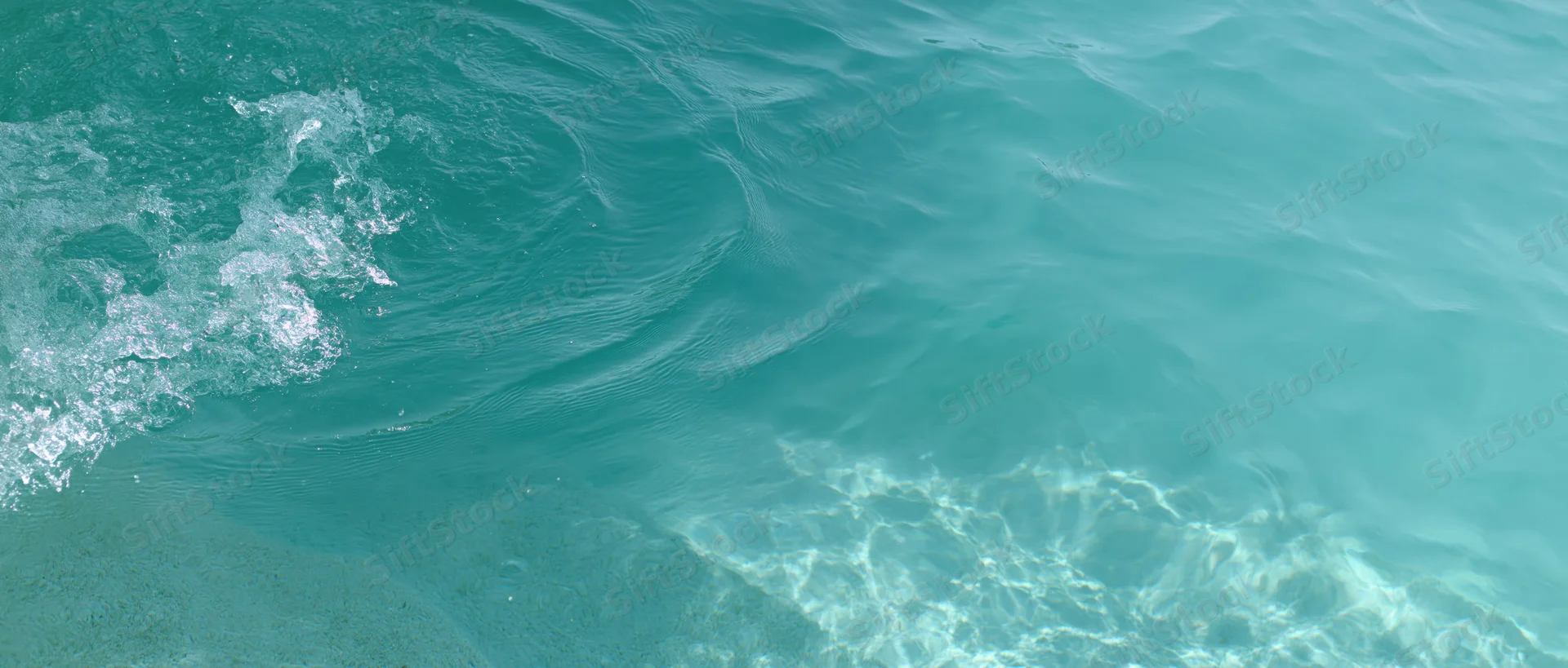 Turquoise ocean water with gentle waves and sunlight reflections over shallow seabed