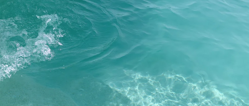 Turquoise ocean water with gentle waves and sunlight reflections over shallow seabed