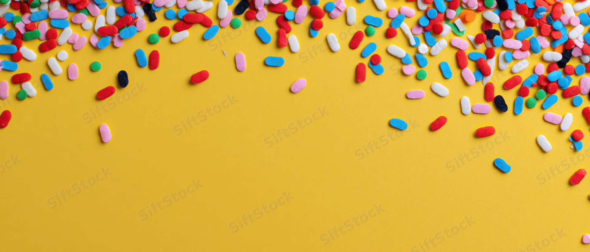 Colorful sprinkles scattered across yellow background with copyspace