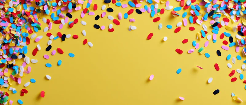 Colorful confetti scattered across yellow background with copyspace for text or design