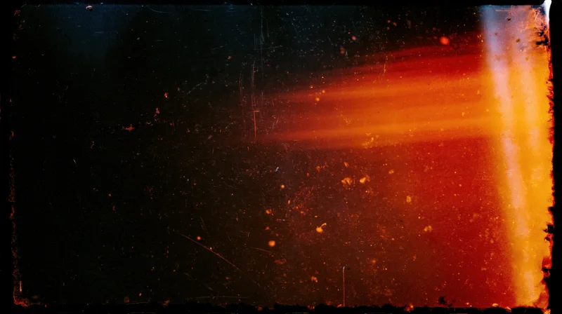 Abstract light flare with orange and red glow and scattered particles on dark background