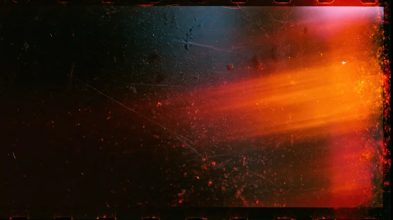 Abstract light flare with orange and red glow and floating particles on dark background, framed with film sprocket holes and grainy texture
