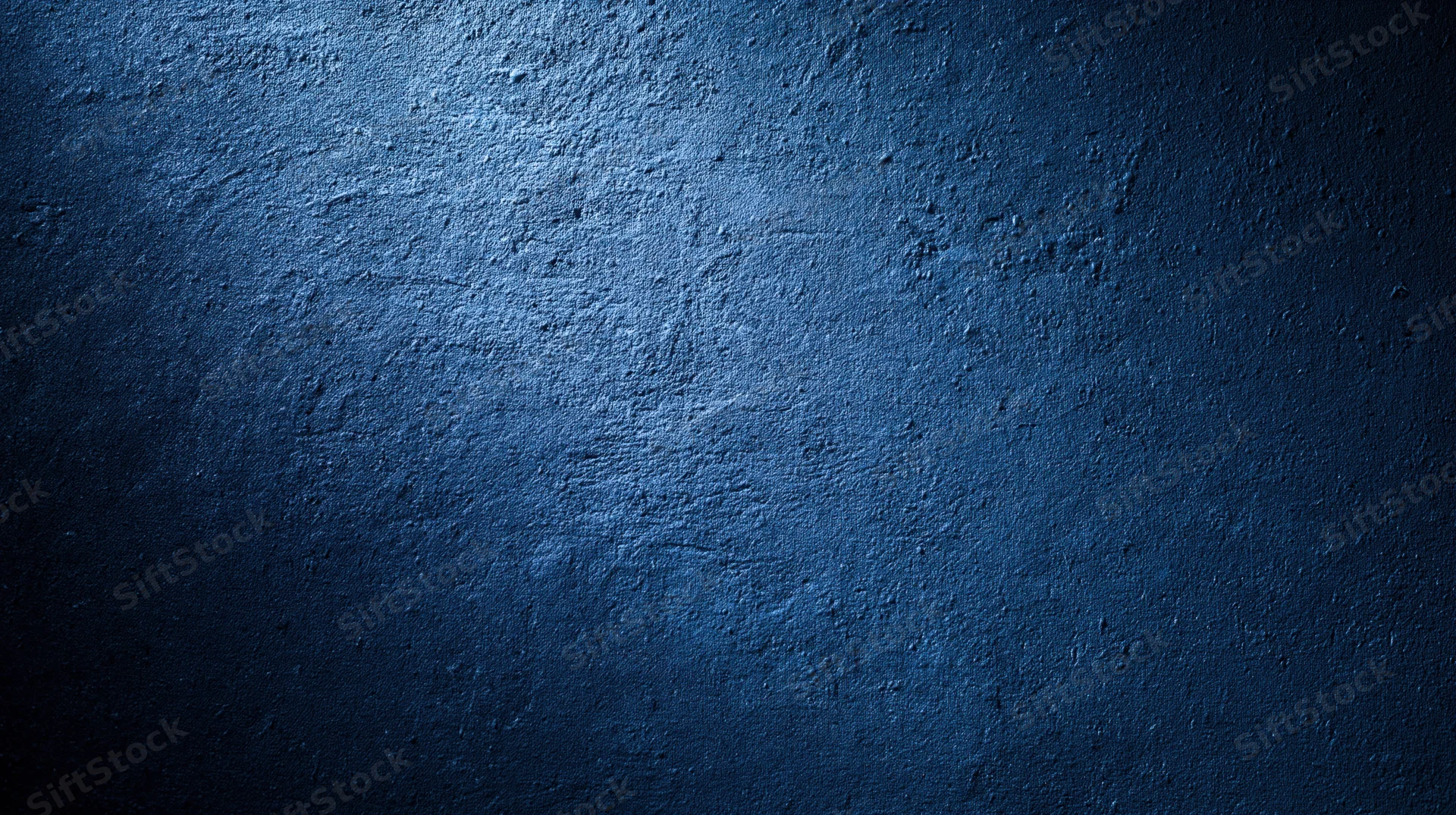 Textured blue concrete wall with gradient lighting and copyspace
