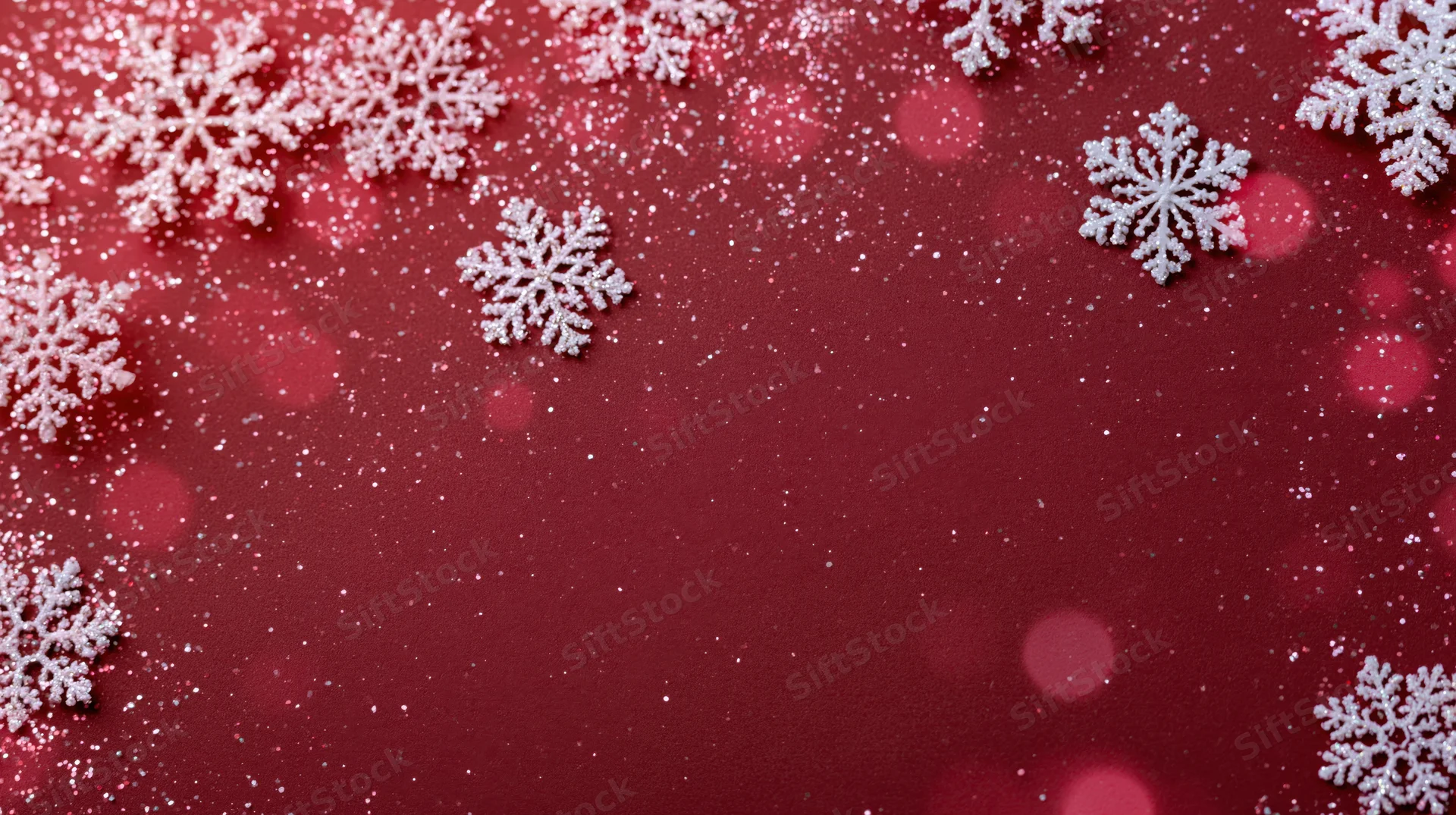 White snowflakes scattered on a red glittery background with bokeh lights and copyspace in center