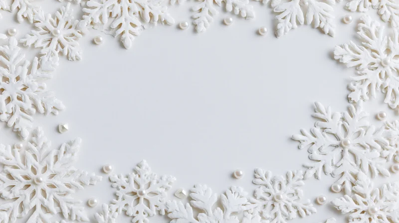 White snowflake decorations arranged in a border frame with pearls on a plain white surface