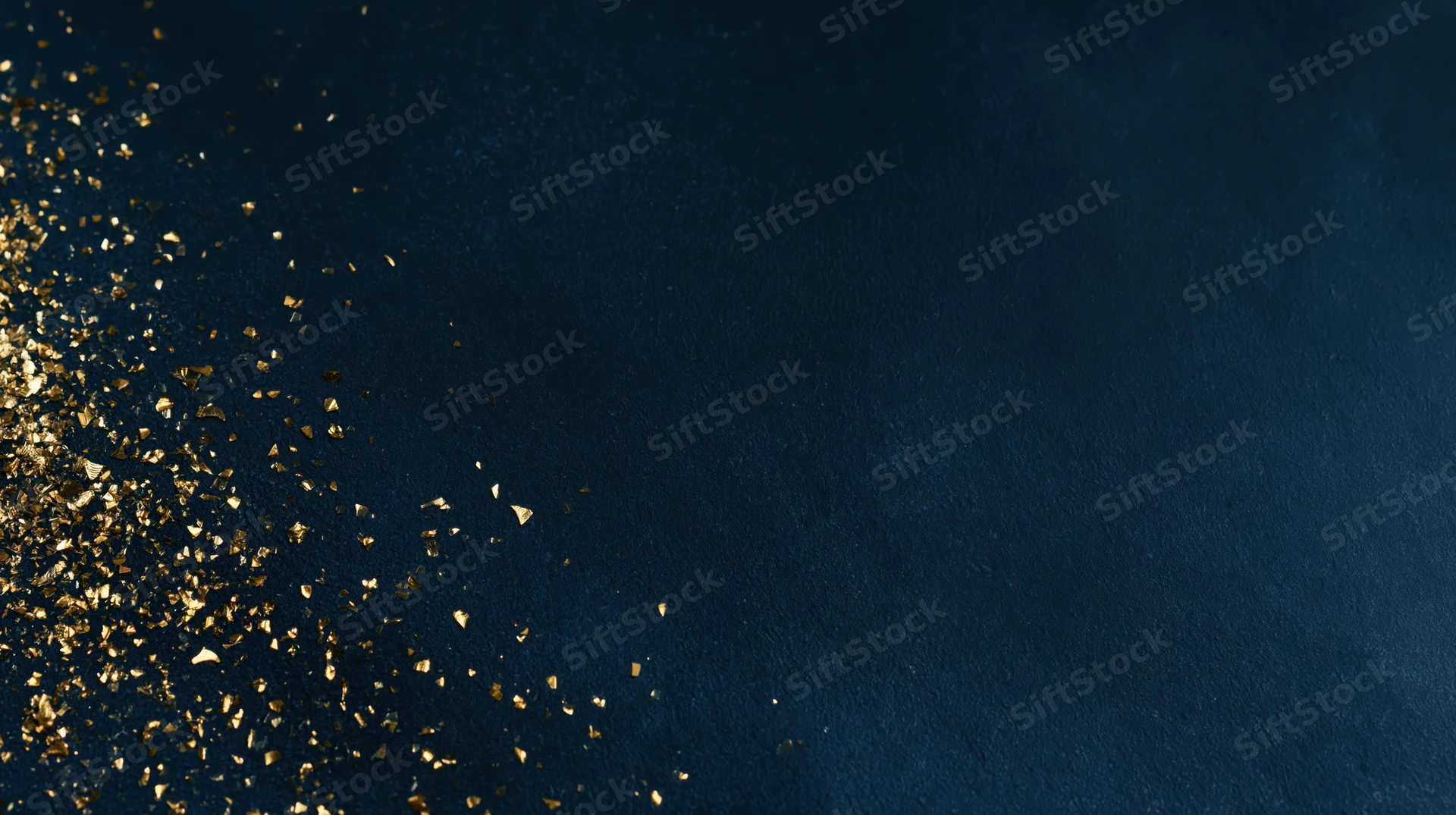 Gold glitter particles scattered across dark navy blue textured background with copyspace