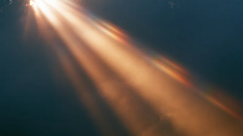 Sunbeams radiating through hazy sky with lens flare and warm glow