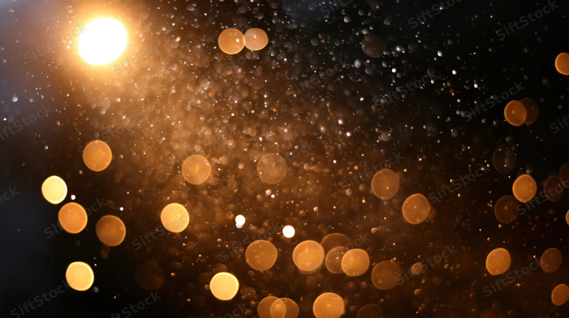 Blurred golden lights scattered across a dark background with soft glow and bokeh effect
