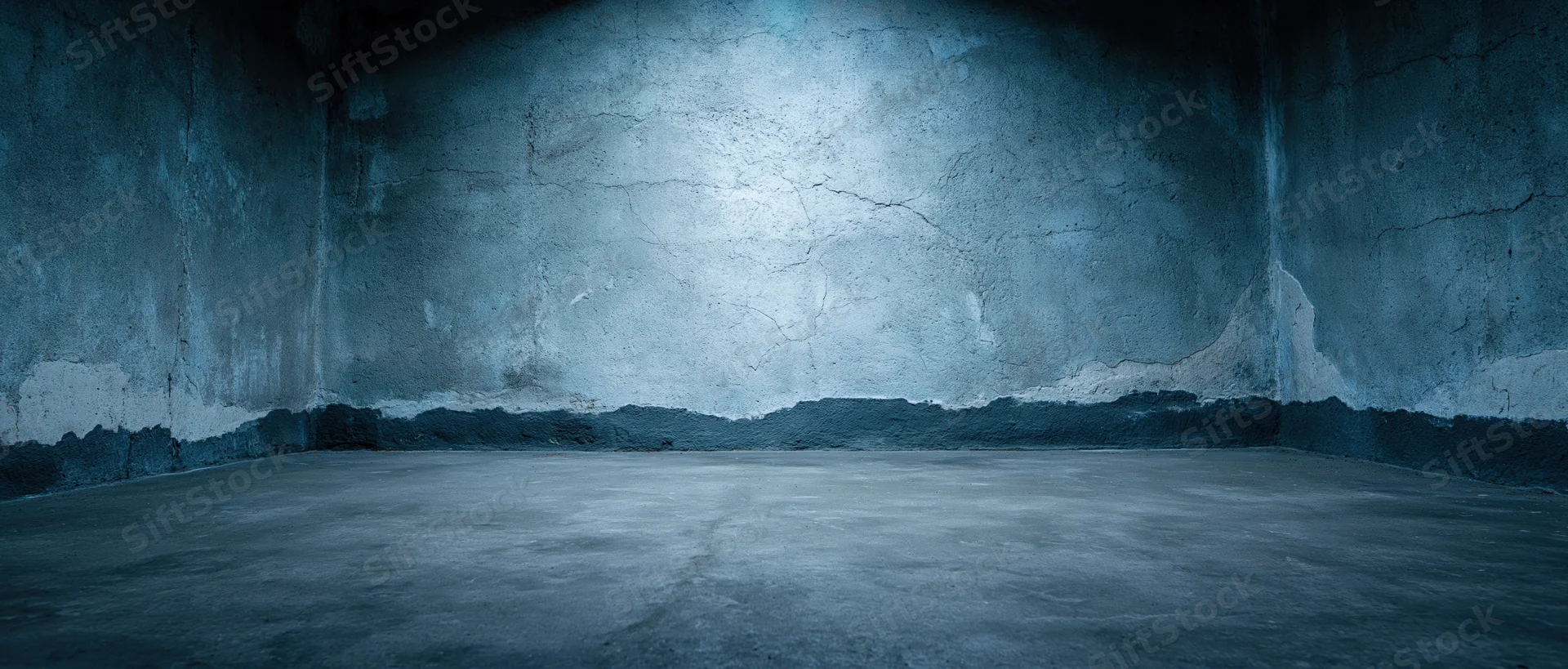 Empty concrete room with cracked walls and dim lighting in a basement interior