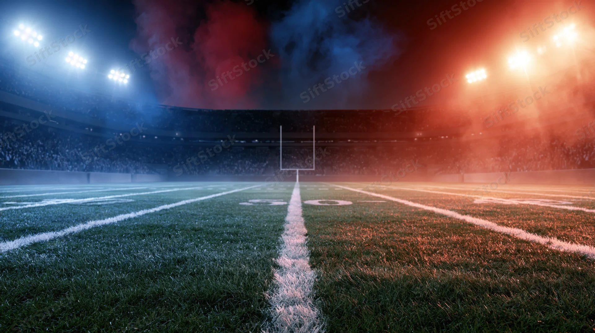 Football field at night with goalpost and smoke under stadium lights