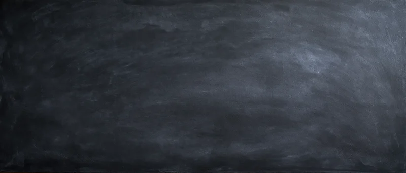 Dark smudged blackboard surface with chalk residue showing erased writing in a classroom setting